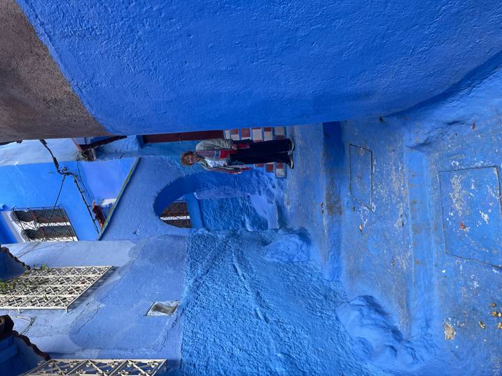 Ruelle étroite bleue à Chefchaouen, avec une personne debout.