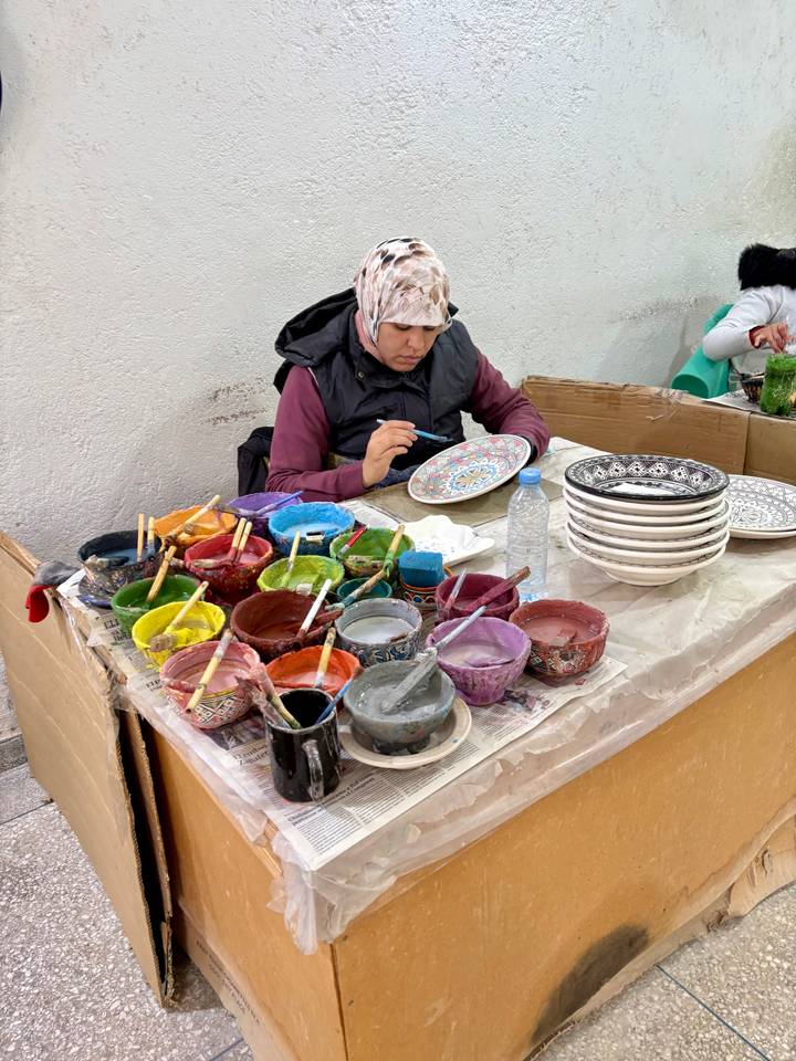 Personne peignant des céramiques traditionnelles avec des peintures colorées.