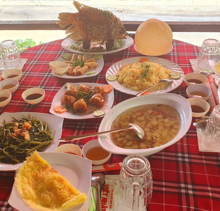 Mesa llena de platos vietnamitas sobre un mantel a cuadros.
