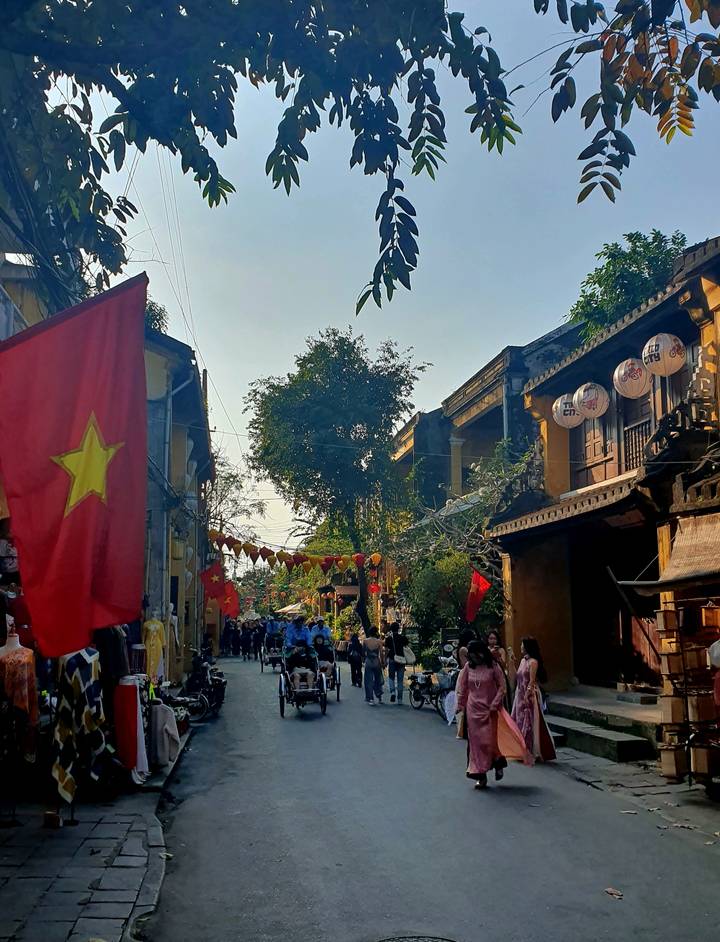 Escena callejera con banderas vietnamitas y arquitectura tradicional.