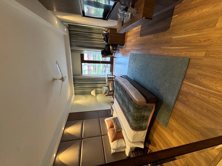 Habitación de hotel espaciosa con una cama, sillas y una ventana grande.