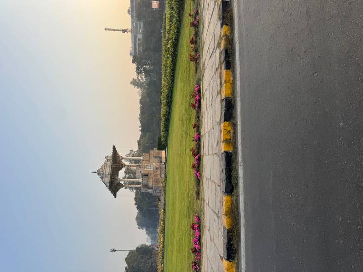 Pabellón de piedra en un jardín rodeado de flores.
