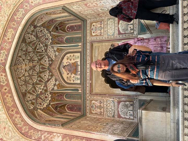 Pareja de pie frente a un arco decorado.