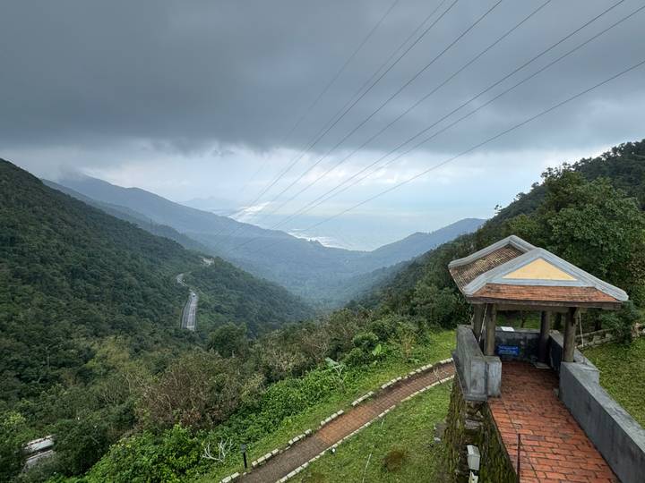 Vue panoramique de montagne d'une route sinueuse traversant des forêts denses sous un ciel nuageux.