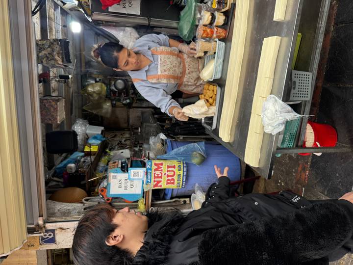 Vendedor de comida callejera preparando comida con clientes observando.