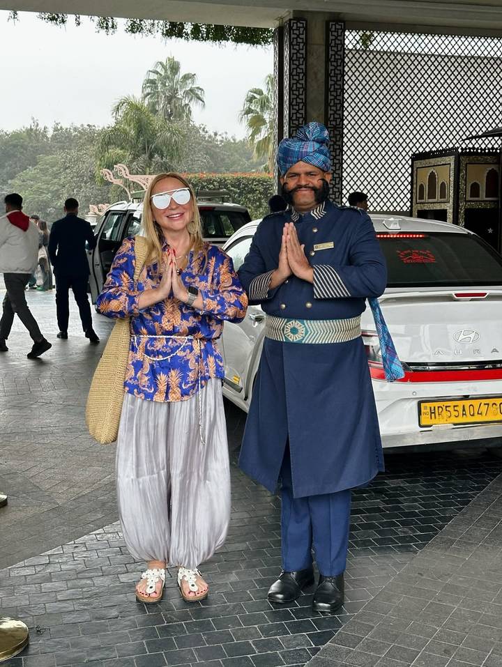 Dos personas posando con saludo tradicional indio frente a un coche.