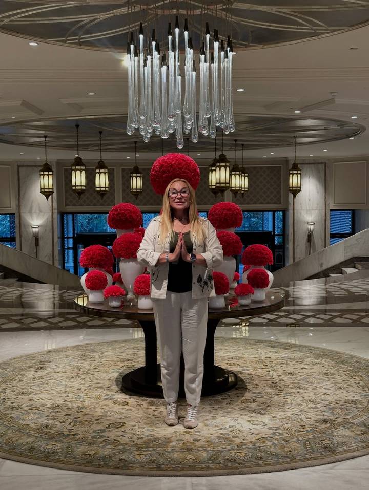 Persona parada frente a una exhibición de arreglos florales rojos.