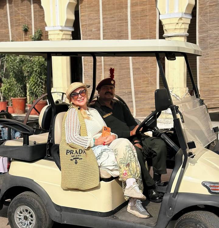 Una mujer sentada en un vehículo tipo carreta con un conductor en uniforme.