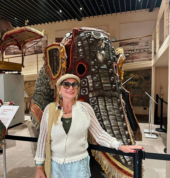 Persona posando frente a una exhibición de elefante decorado.