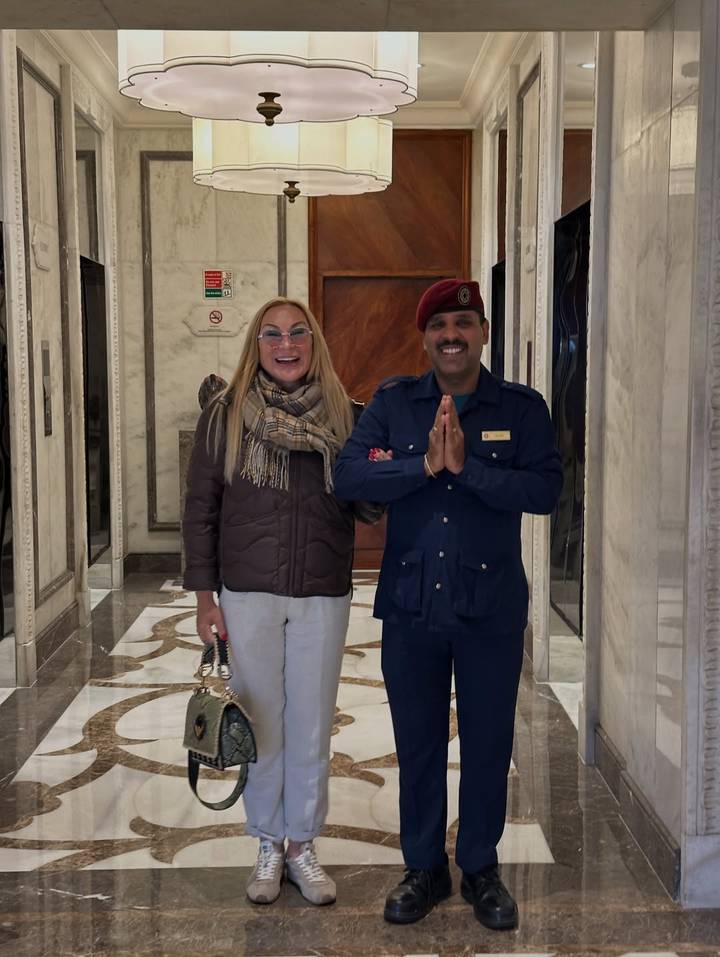 Dos personas posando dentro de un pasillo con pisos de mármol.