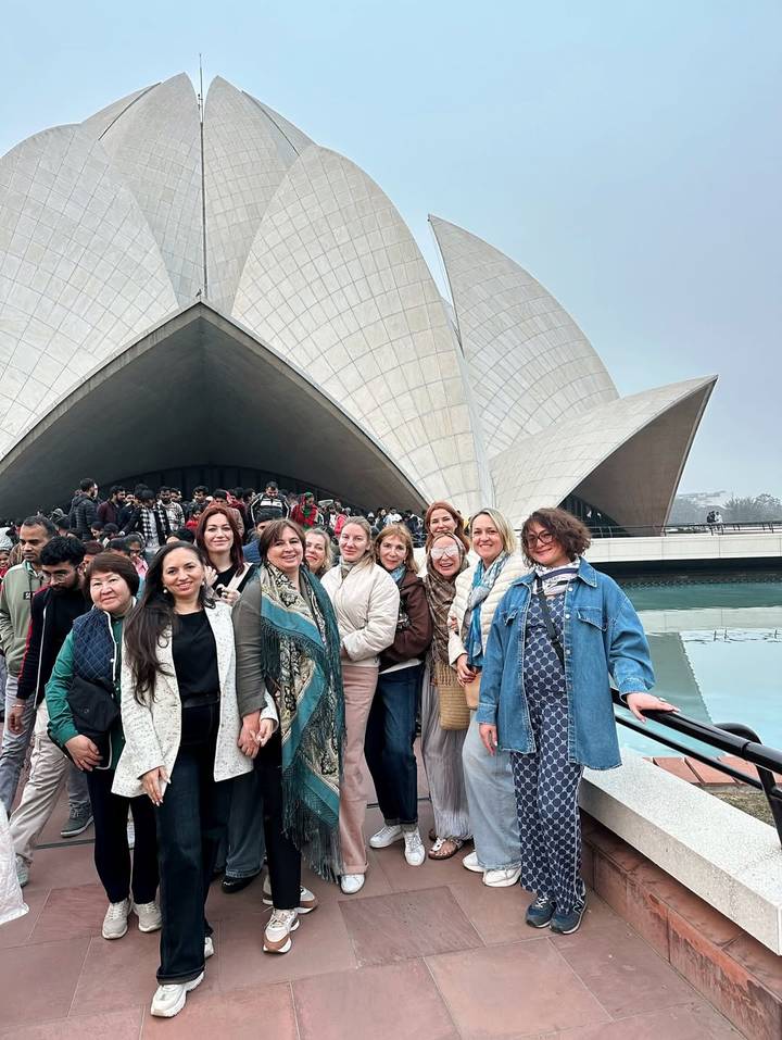 Grupo de mujeres posando frente a un gran edificio en forma de loto.