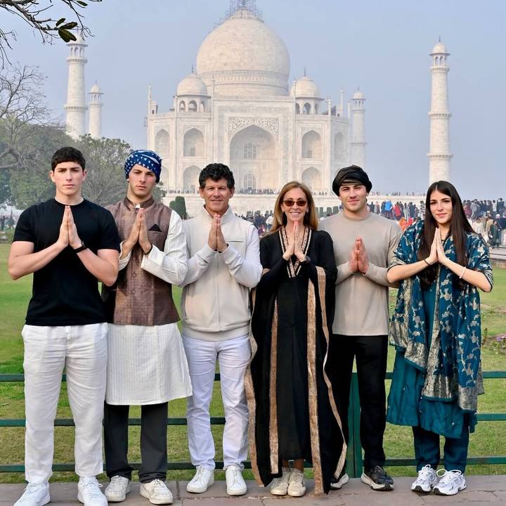 Une famille les mains jointes posant devant le Taj Mahal.
