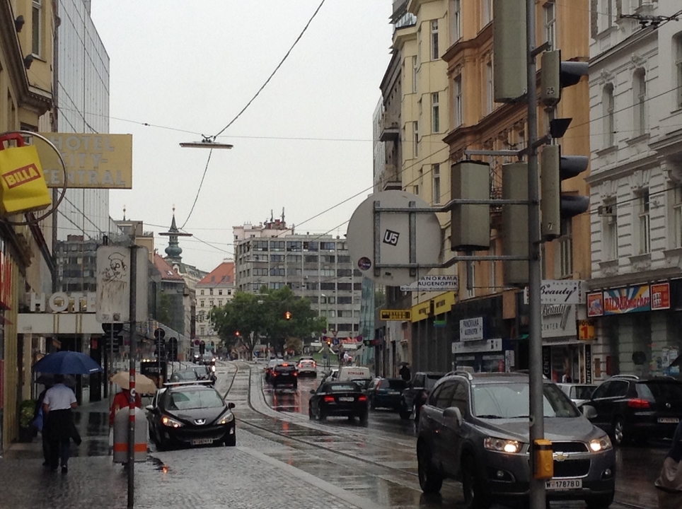 A busy city street with cars, buildings, and pedestrians.