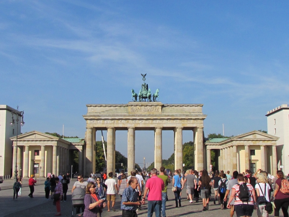 The Brandenburg Gate in daylight with many pedestrians.