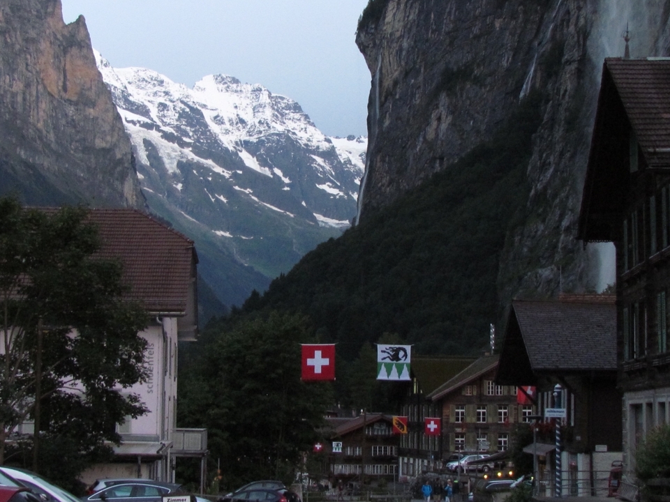 Alpine village with mountains and Swiss flags.