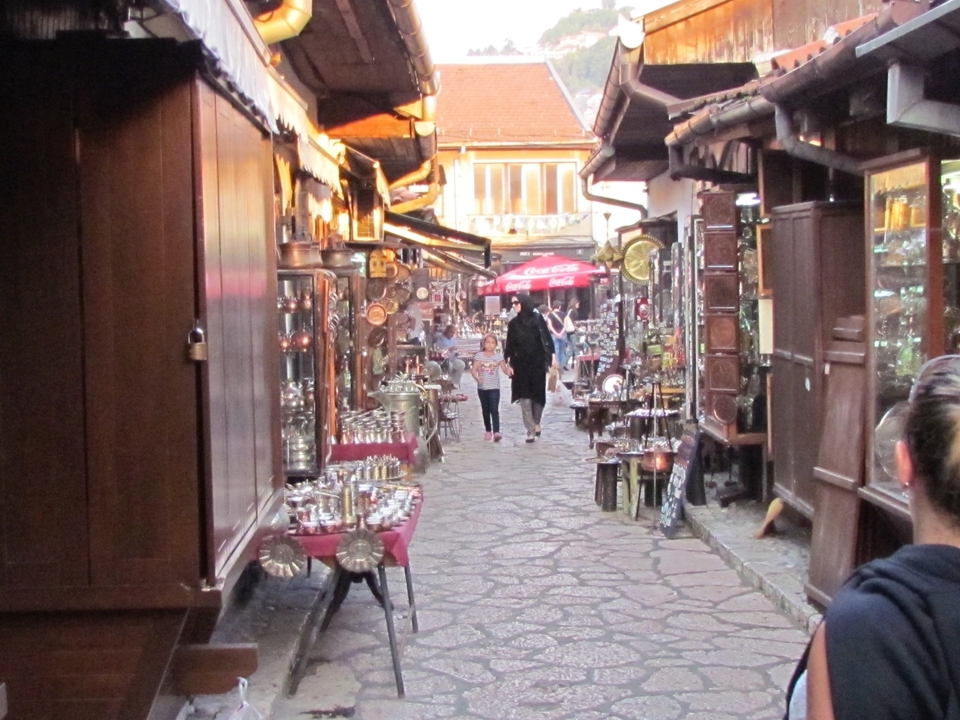 Narrow market street filled with shops and people.