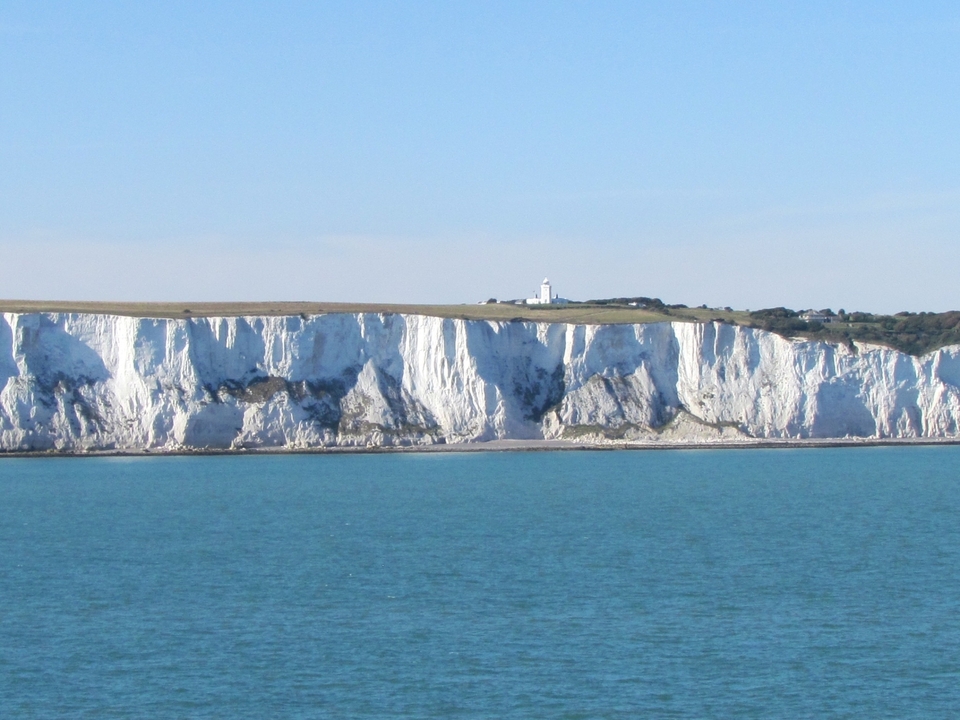 White cliffs along the coastline with a lighthouse.