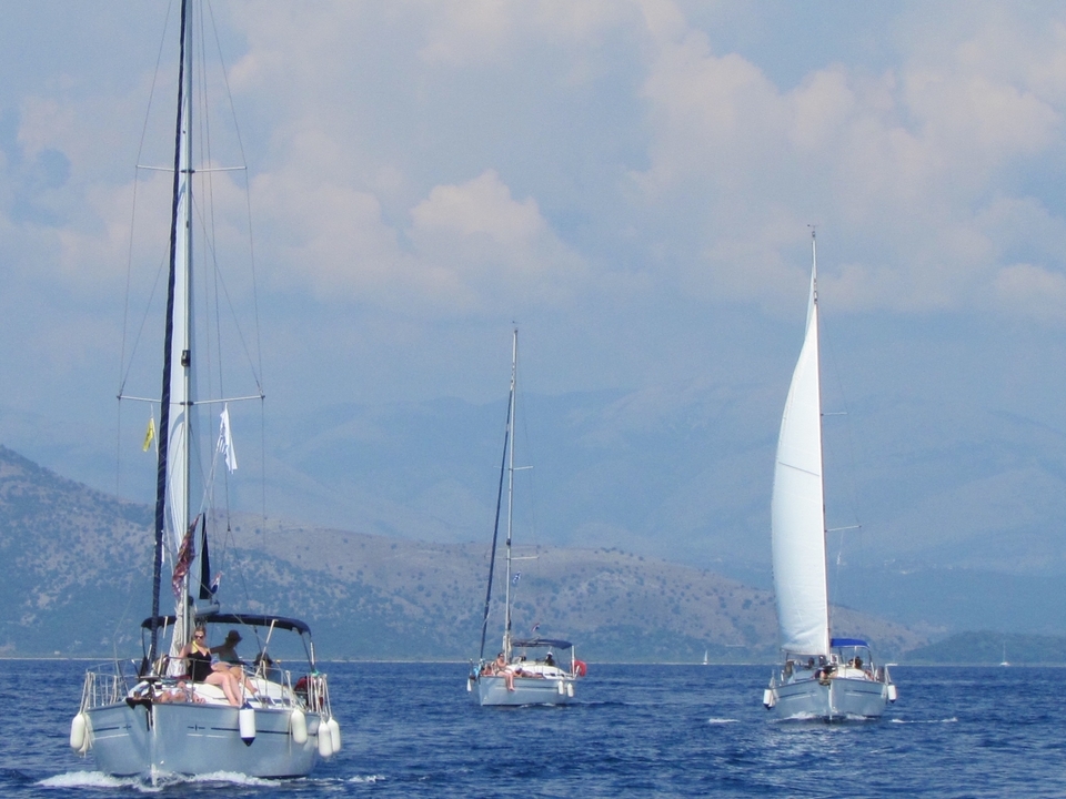 Sailboats on the sea with mountainous background.
