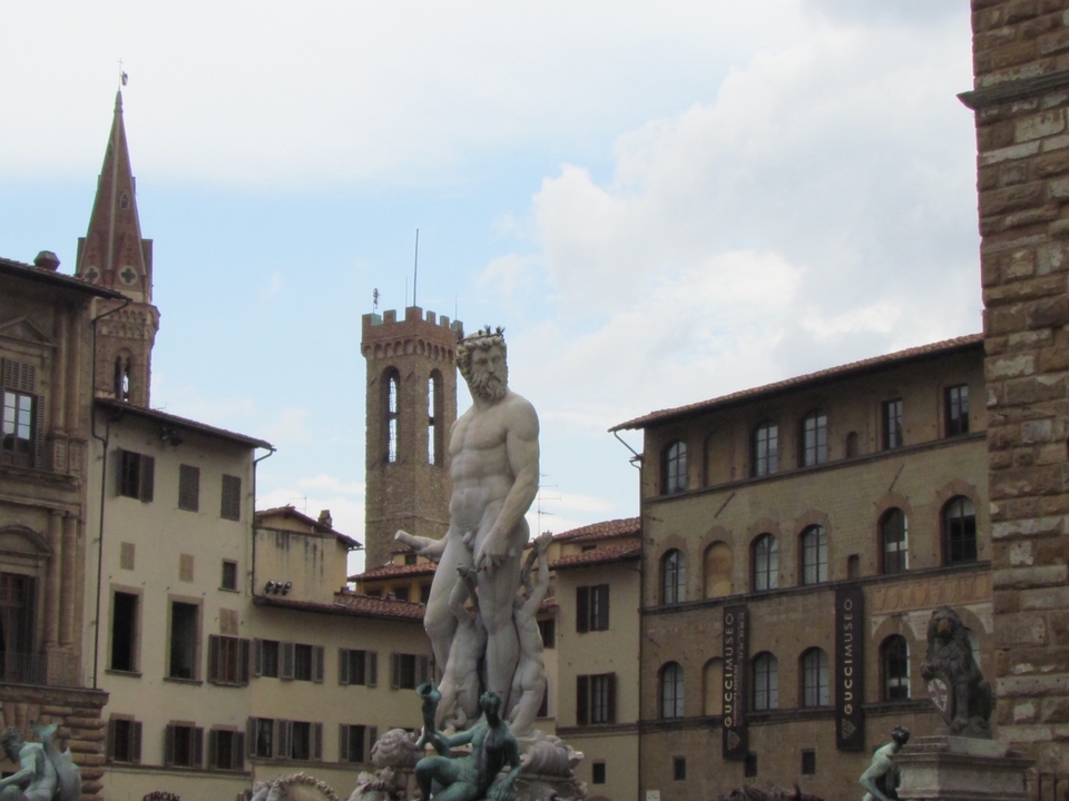 Statue in front of historic buildings with a clock tower.