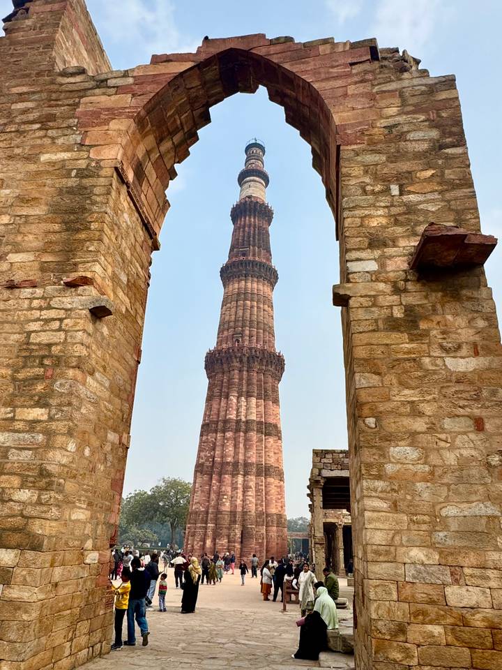 Le Qutub Minar encadré par des arches de pierre.