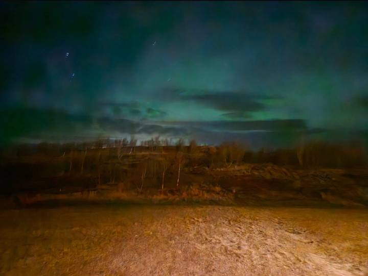 Ciel nocturne avec de faibles aurores visibles au-dessus d'un paysage aride.