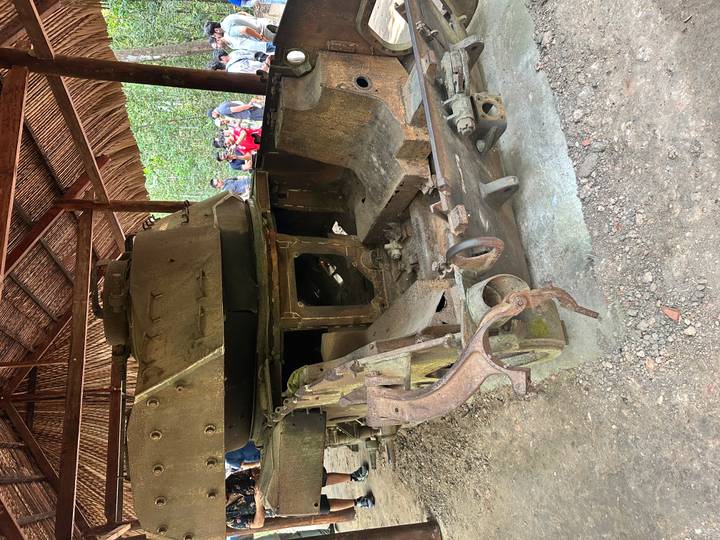 Tanque oxidado expuesto al aire libre con visitantes alrededor.