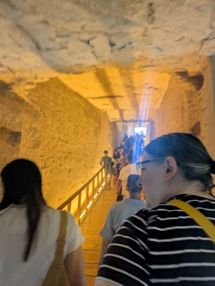 Personas caminando dentro de un pasadizo antiguo con poca iluminación.
