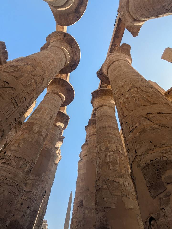 Altas columnas antigas con jeroglíficos contra un cielo azul.