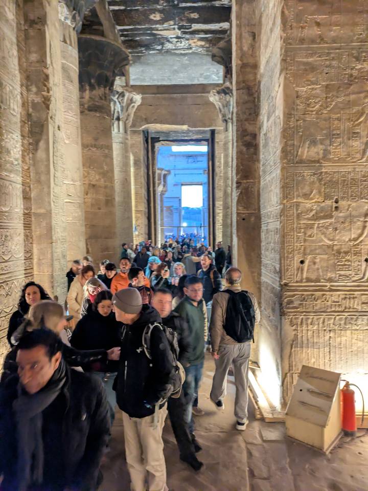 Multitud de gente dentro de un templo antiguo con paredes talladas.