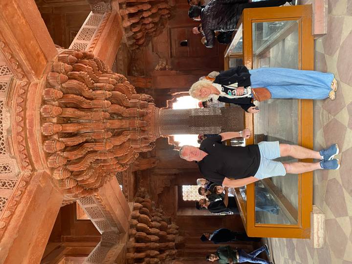 A couple standing under an intricately carved stone structure.