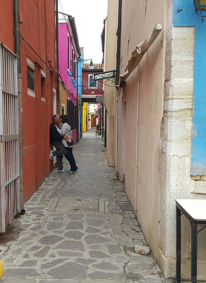 Couple s'embrassant dans une ruelle étroite et colorée.