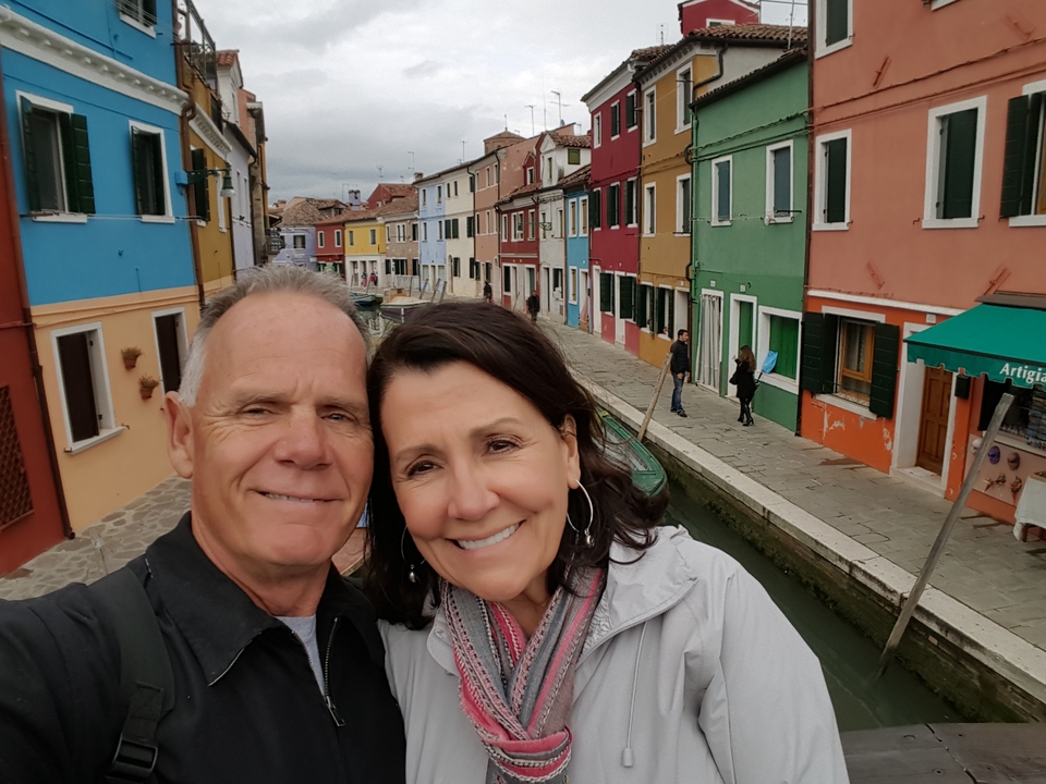 Couple posant devant des maisons colorées au bord d'un canal.