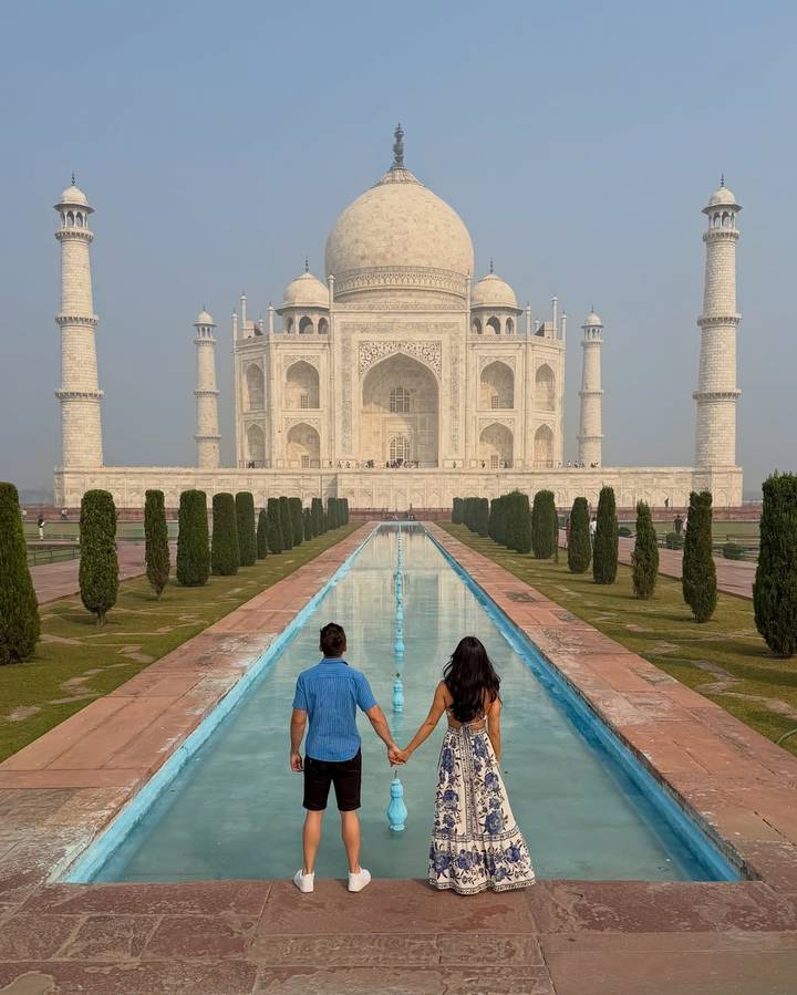 Una pareja tomada de la mano frente al Taj Mahal.