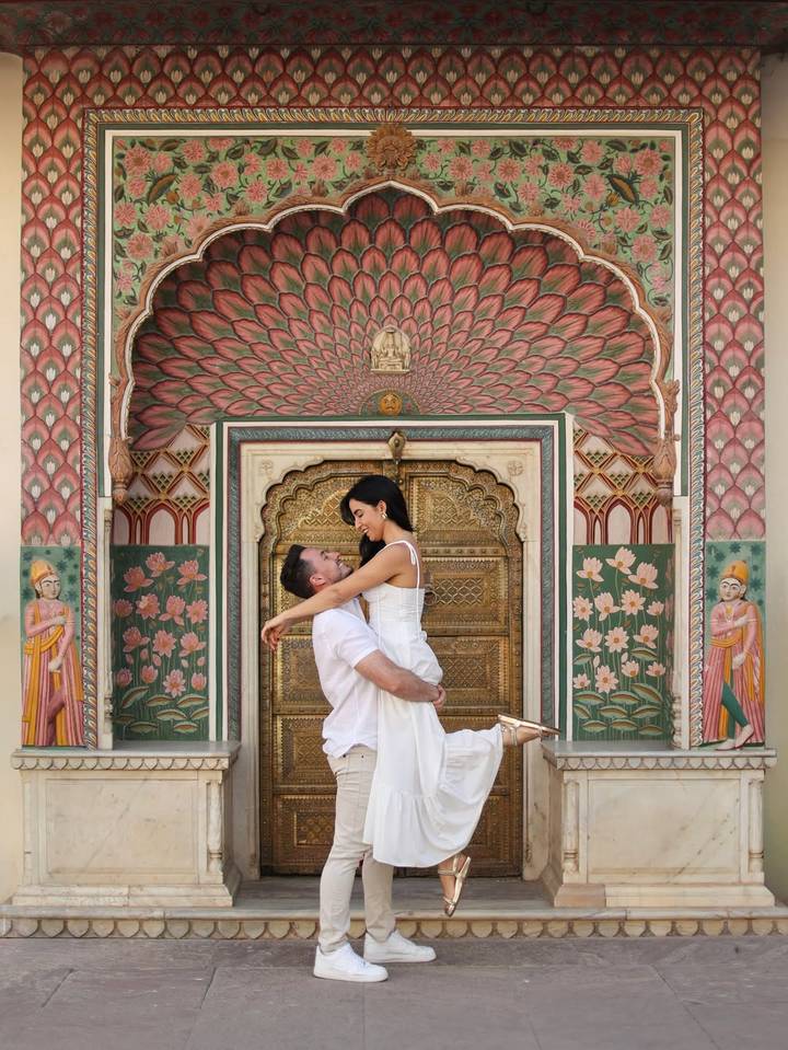 Una pareja abrazándose frente a un arco intrincadamente decorado.