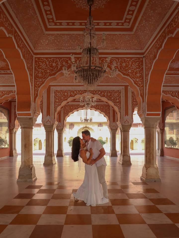 Una pareja besándose en un salón ornamentalmente decorado.