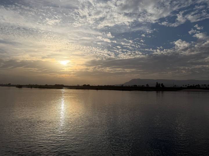 Atardecer sereno sobre un río ancho con nubes en el cielo.
