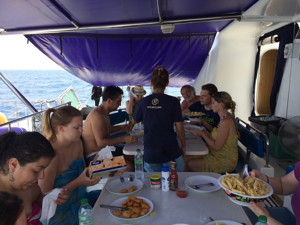 Personnes dînant sur un bateau avec la mer en arrière-plan.