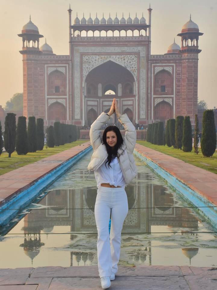 Persona posando frente a edificio histórico icónico con estanque reflectante