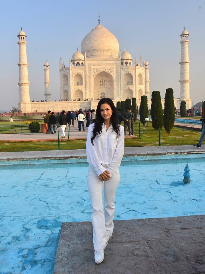 Persona parada frente al Taj Mahal con visitantes en el fondo