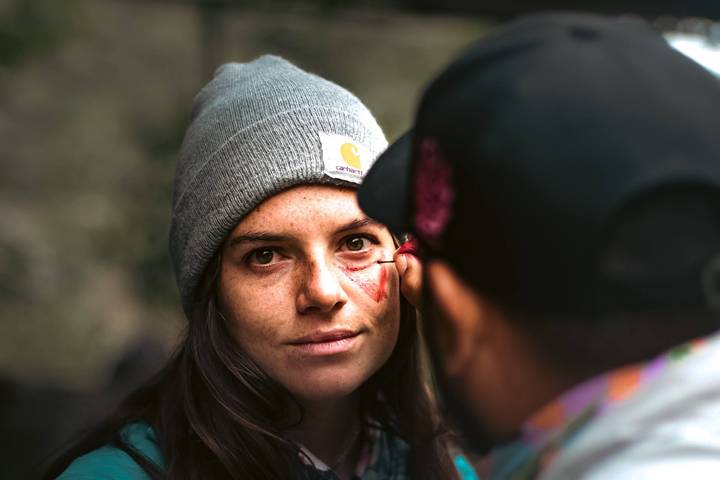 A person getting face paint from another person in a casual outdoor setting.
