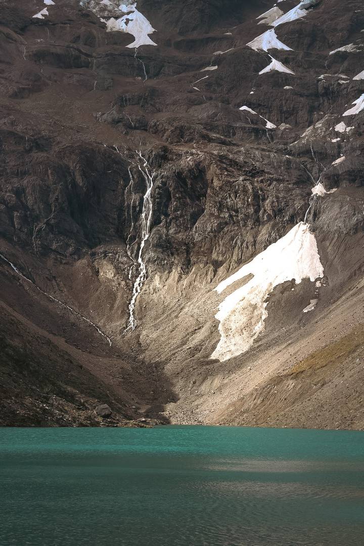 A rugged mountainous terrain with snow patches and rock formations.