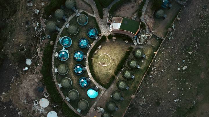 An aerial view of a clustered arrangement of geodesic domes and landscape.