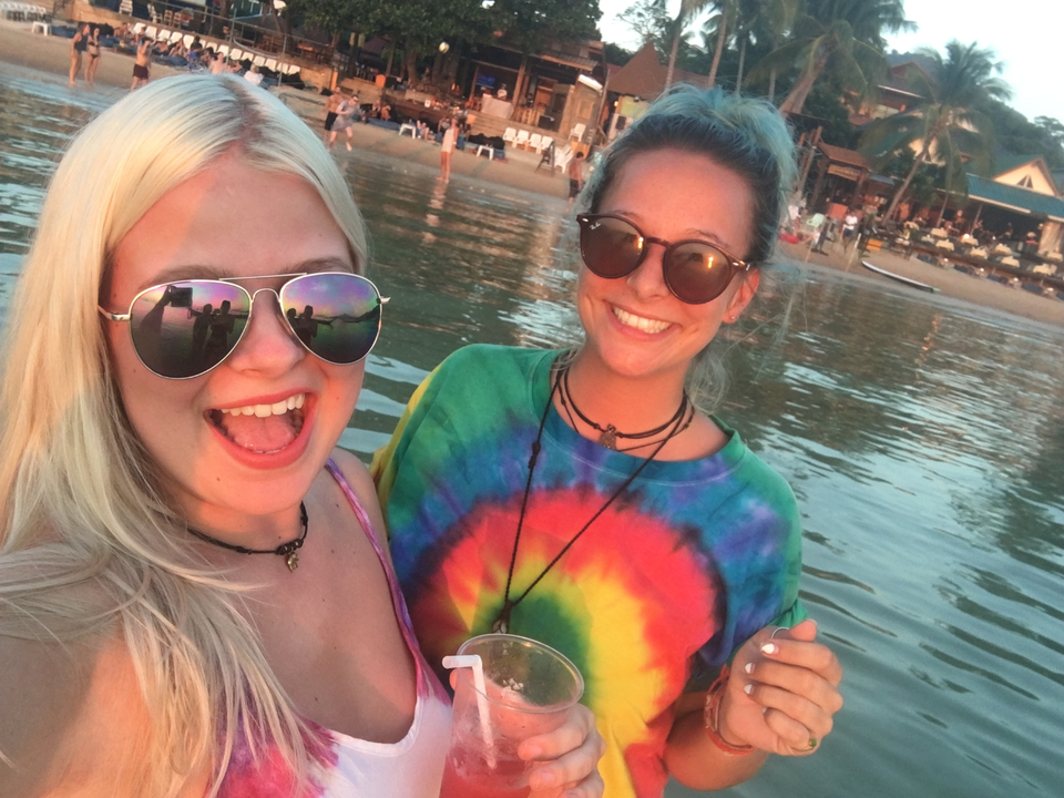 Two women taking a selfie on the beach at sunset.