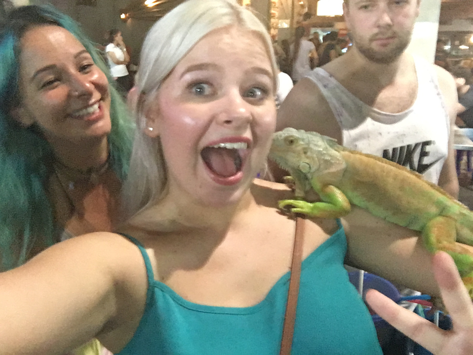 Two women with an iguana, laughing and posing.