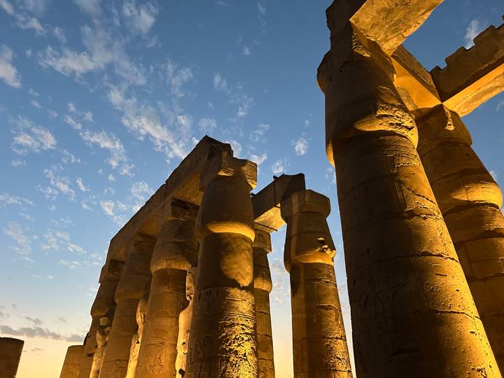 Illuminated ancient columns against a twilight sky.