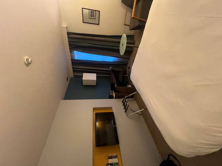 Habitación de hotel con cama, silla y televisor.