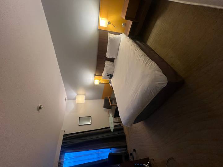 Habitación de hotel con cama y lámparas de noche.