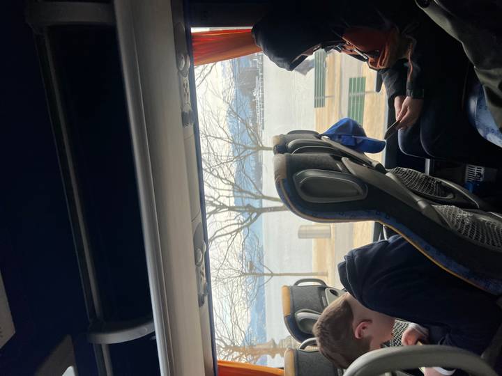 Vista desde el interior de un autobús con personas mirando hacia afuera a un lago.