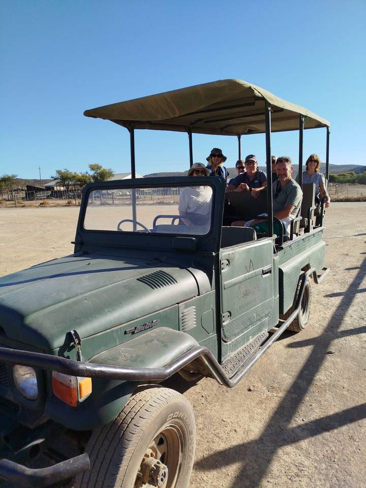 Eine Gruppe von Menschen in einem offenen Safari-Fahrzeug inmitten eines Safari-Parks.
