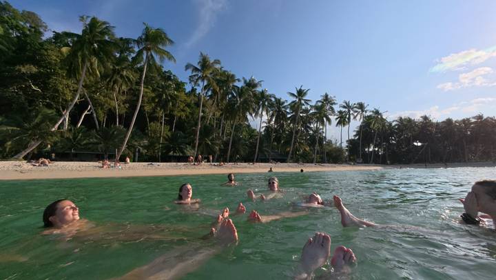 People floating in clear water at a beach.